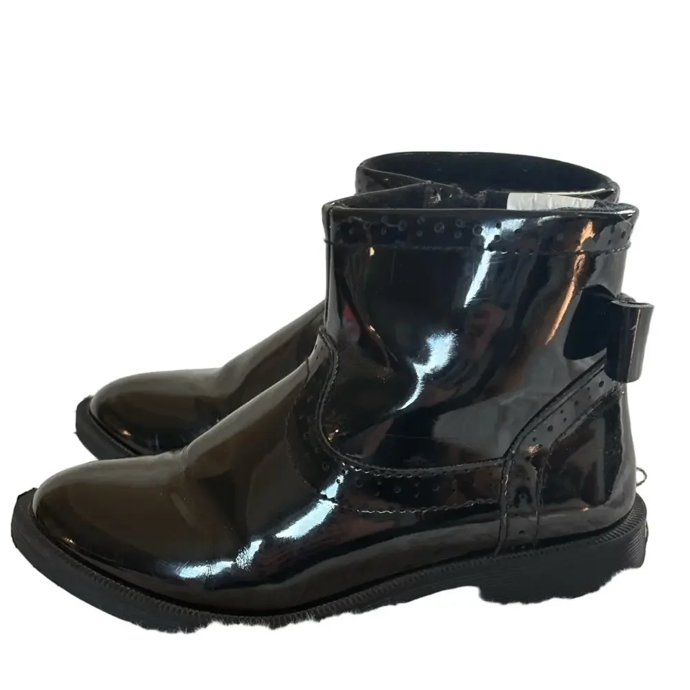 Little girls glossy black boots with bow on the back.